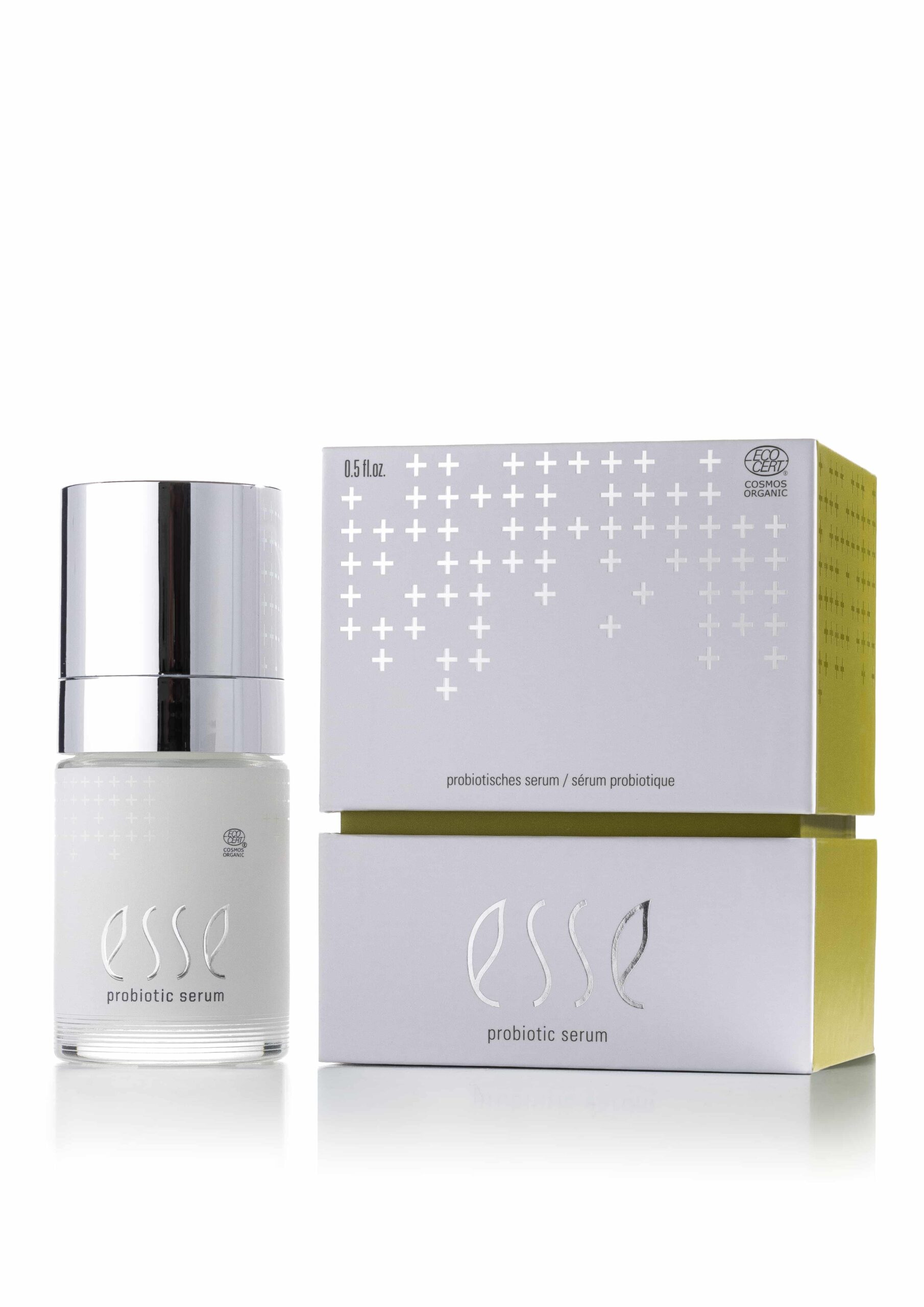 The Esse Probiotic Serum with a silver cap is shown beside its minimalist white and yellow box, both featuring silver-embossed branding.