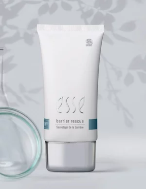 A white tube labeled “Import placeholder for 57617” stands upright on a light surface with a blurred glass container and leafy shadows in the background.